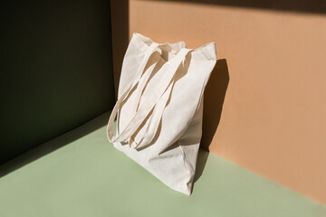 Fototapeta na wymiar Reusable cotton shopping bag on green and beige background. Zero waste concept. No plastic