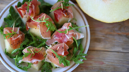 Melon jamon appetizer on a plate. Melon prosciutto salad on skewers.
