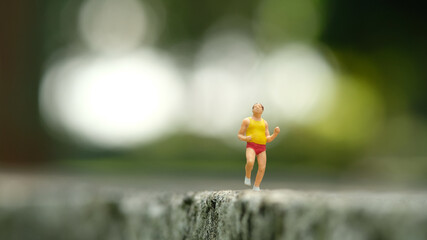 Miniature people toy figure photography. Solo jogging. A fat men running at park outdoor track
