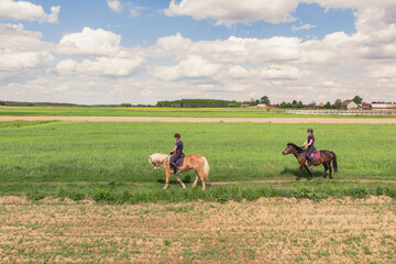 Two horse riders on a Palomino horse and a Dark Bay Horse moving across the beautiful farm field...