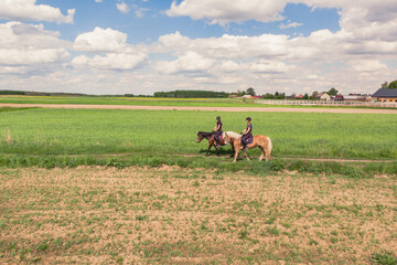 Two horse riders on a Palomino horse and a Dark Bay Horse moving across the beautiful farm field...