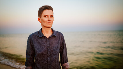 An androgynous woman with short hair on a sandy beach