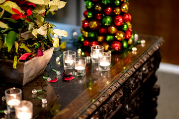 Little candle in small glass near the decorated Christmas tree