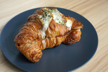 Cheese and meat croissant in a plate on a wooden table              