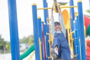 A little girl in casual clothes playing on kids playground, holding and climbing. Selective focus...