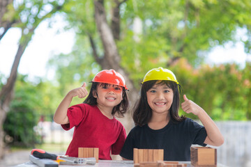 Asian Siblings girls wearing engineering hats building House from the wooden toy. To learning and enhance development, little architect.