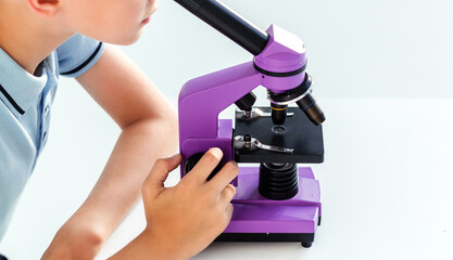 Boy in blue polo looks through a purple microscope