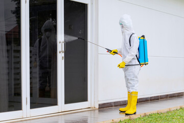 Man spraying disinfectant to glass door in hospital