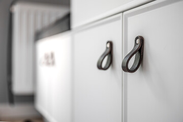 Close-up of black knobs on a white cabinet.