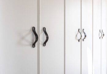 Close-up of black knobs on a white cabinet.