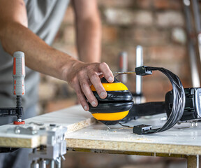 Closeup professional carpenter workplace with protective headphones.