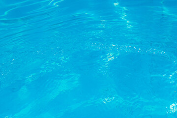 Fototapeta na wymiar Beautiful blue ripple water surface in swimming pool with sun reflection