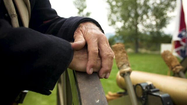 Close up of Civil War Soldier next to canon with confederate flag in the back drop out of focus