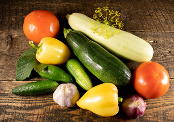 Beautifully laid out vegetables on a wooden table.Peppers,tomatoes,cucumbers,zucchini, Garlic,dill and parsley lying on a wooden table.