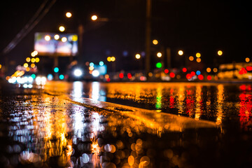 Rainy night in the big city, the light from the headlamps of approaching car on the highway. View...