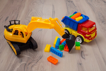 Children's toy. Plastic truck and tractor excavator loading multi-colored blocks.