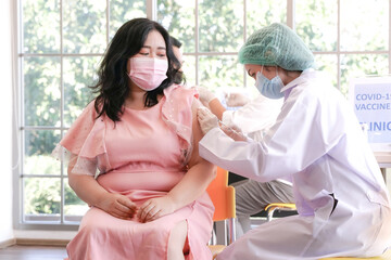 Overweight asian woman giving her arm to nurse for injection vaccination against Covid 19 infection...