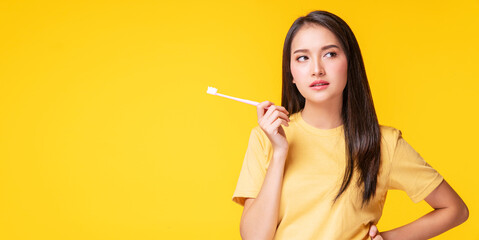 Health care dentist oral concept. Unhappy young woman serious toothache holding toothbrush in her hand while standing over isolated blue background. Sad girl sick problem teeth touching her face.
