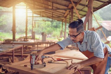 Closeup of a man carpenter using a nail gun.Carpenter using air nail gun doing wooden furniture work