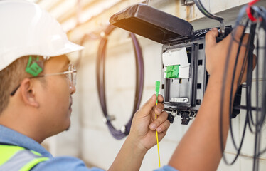 An internet technician is repairing or maintaining a fiber optic connection by opening a fiber optic connector. - obrazy, fototapety, plakaty
