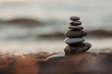 Pyramid of stones on the beach at sunset, beautiful seascape, rest and seaside vacation concept. 