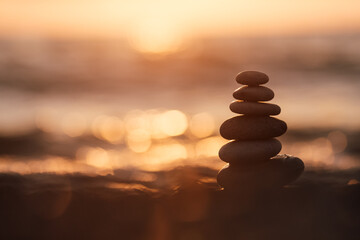Pyramid of stones on the beach at sunset, beautiful seascape, rest and seaside vacation concept. 