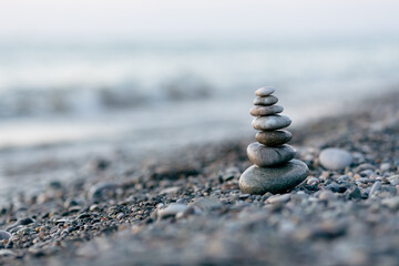 Pyramid of stones on the beach at sunset, beautiful seascape, rest and seaside vacation concept. 