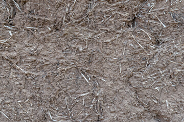 Old clay and straw wall of clay and wood huts of a mazanka, mud hut close up. Mud background