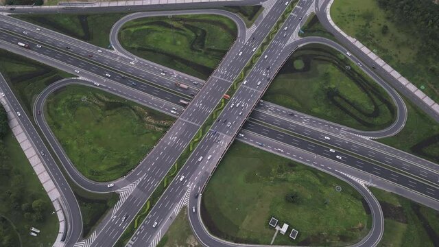 Aerial top down follow road of elevated modern traffic junction and raising up to cityscape view of Chengdu metropolis city developed Tianfu New area. Motion of vehicles on intersection.