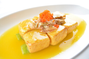 braised handmade bean curd tofu with crabmeat, luffa plant, roe in golden yellow sauce in white background asian halal menu