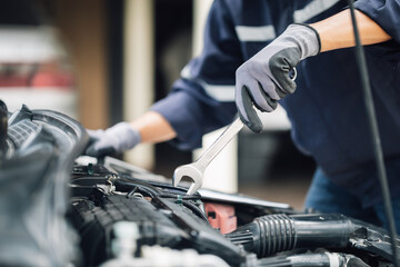 Mechanic works on the engine of the car in the garage. Repair service. Concept of car inspection service and car repair service.