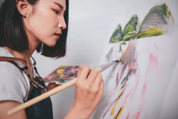 Fotobehang Asian woman artist painting picture with blank canvas side view, using paint brush and colour pallets having fun creativity activity occupation hobby concept, creative thinking imagination visual © Have a nice day 