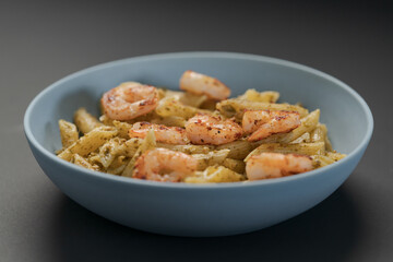 Penne pasta with shrimps and pesto in blue bowl