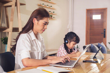 Asian parent mother working at home and daughter studying online class with teacher using tablet...