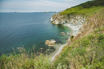 Fototapeta premium summer azure clear sea panorama. shallow transparent sea with reefs, rocks and green hills around. Japan sea. Primorsky Krai in Russia, Putyatina Island