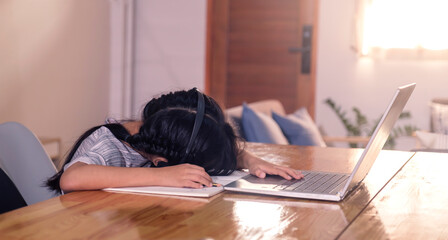 Young Asian girl tired exhausted sleeping studying online class using microphone headset, teacher...