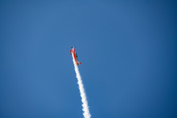 the red plane makes difficult turns and blows white smoke against the blue sky at the Max-21 aerospace salon in Zhukovsky on July 24, 2021