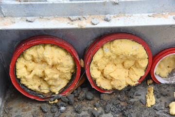 Close-up of plastic pipes filled with industrial foam, laid and poured into concrete.