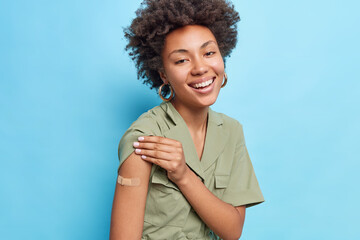 Covid 19 vaccination. Positive Afro American woman shows shoulder with adhesive plaster feels glad...