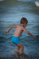 Niño jugando y saltando en la playa