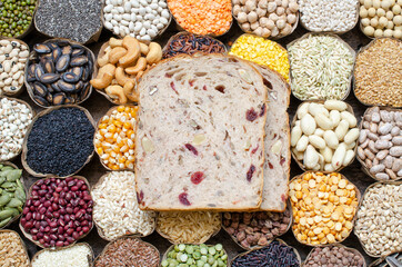 Two pieces of homemade whole wheat and nut bread put on variety kinds of natural organic cereal and grain seed in dry banana leaf bowl on wooden background