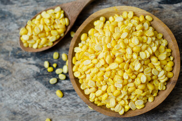 Dry organic yellow mung bean seed pile in wooden bowl and spoon on grunge background