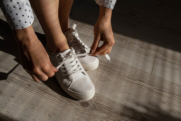 Woman put on new white leather sneakers