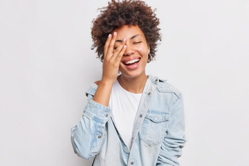 Positive dark skinned young woman makes face palm expresses authentic emotions smiles broadly...