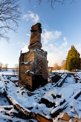 Remains of a burned down house with a brick oven in the middle of a snowy nature