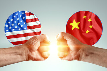 Male hands show their fists against the background of the flags of America and China. The concept...