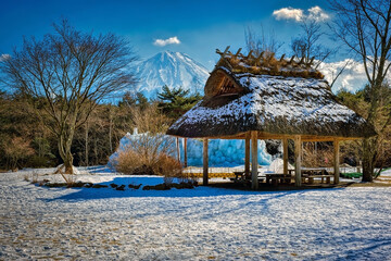 Mid winter snow on a thatched shelter, with a backdrop of Mount Fuji, in Yamanashi Prefecture, Japan