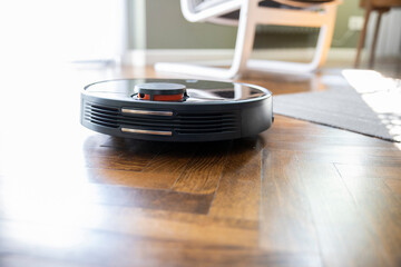 Robot vacuum cleaner on the parquet floor. Cleaning in living room at home