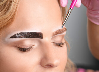 Make-up artist makes markings with white pencil for eyebrow and paints eyebrows. Professional makeup and facial care.