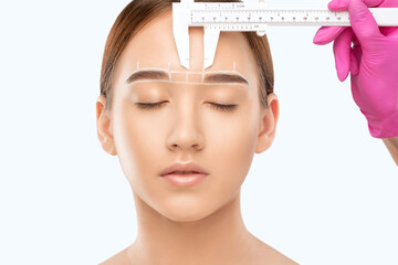 Make-up artist makes markings with white pencil for eyebrow and paints eyebrows. Professional...